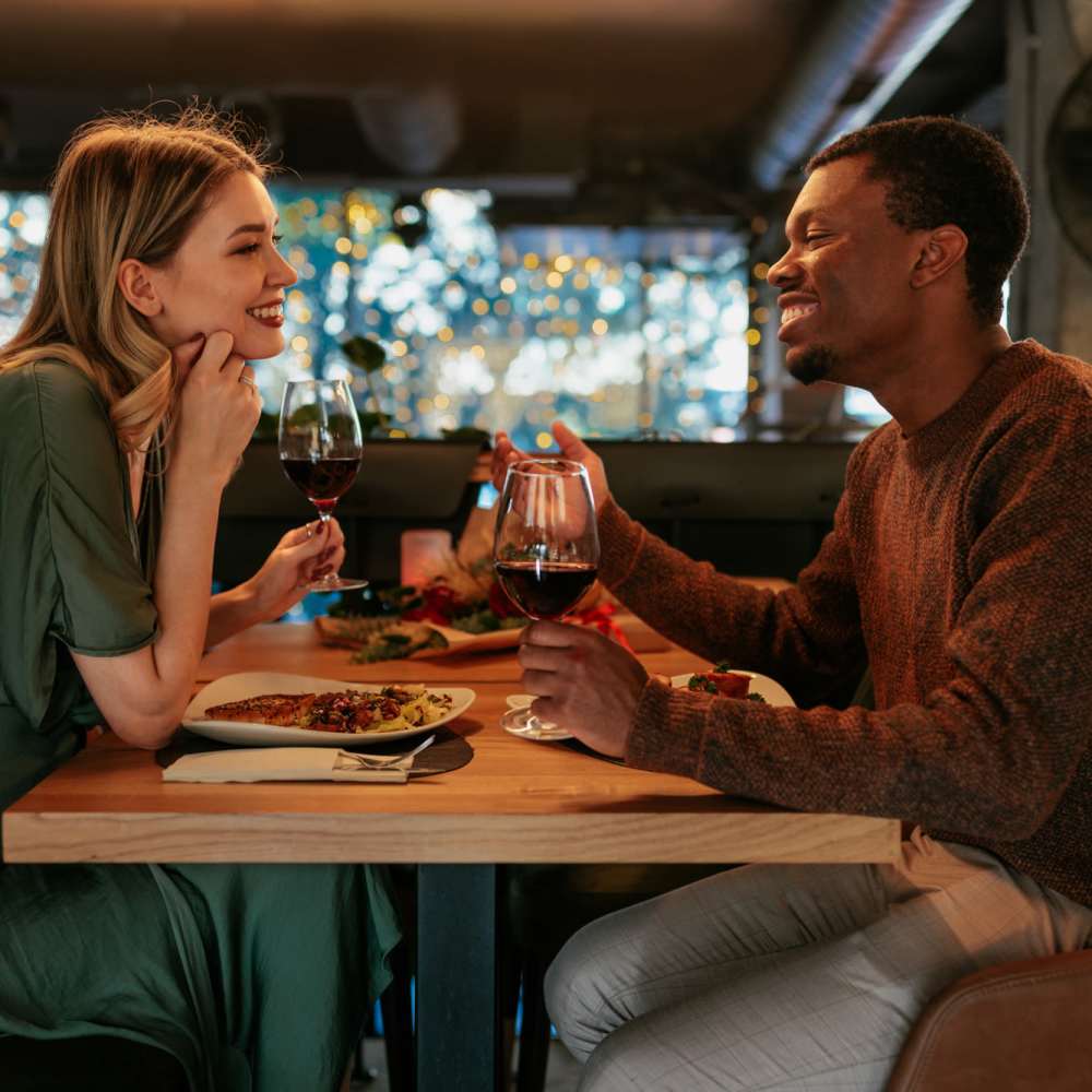 Couple enjoying dinner with red wine at a cozy table with festive lighting near The Arcadia in Madison, Tennessee