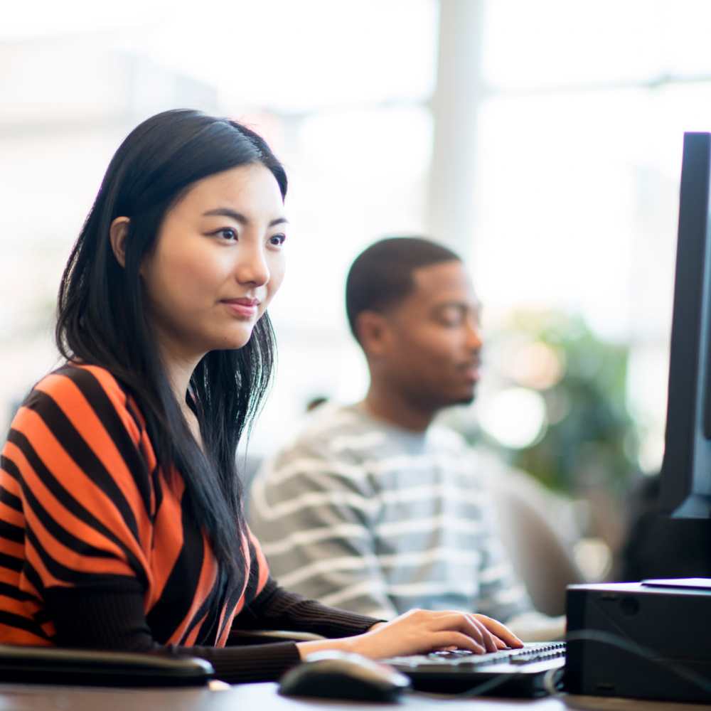 Woman working at computer with man nearby at Niner Woods in Charlotte, North Carolina