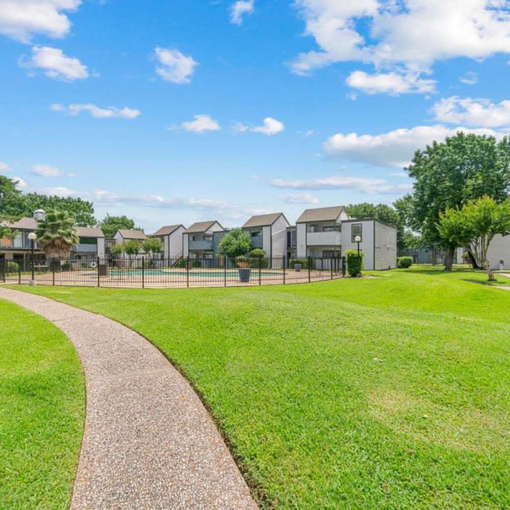 Landscaped courtyard with winding path, grassy lawn, and pool area at The Montclair in Houston, Texas