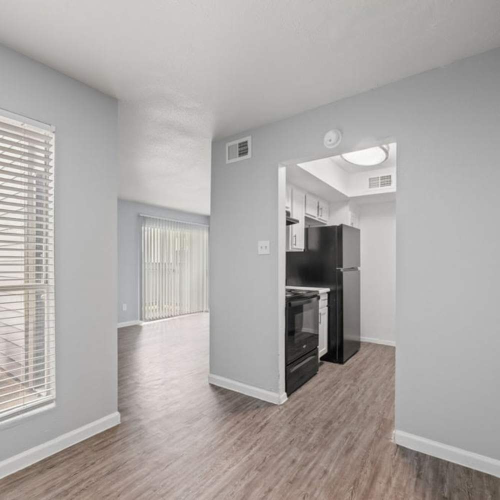 Dining area with window blinds and view into kitchen and living space at The Montclair in Houston, Texas