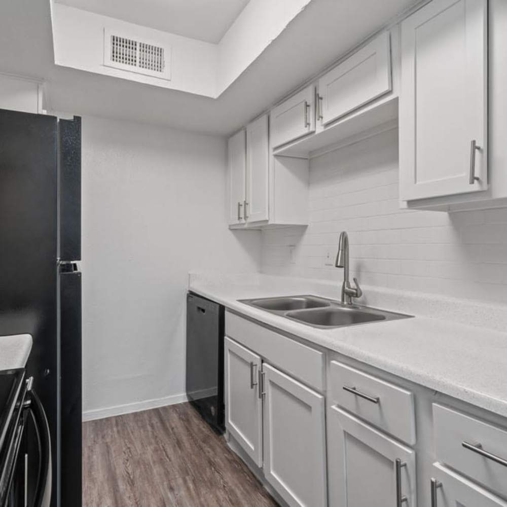 Kitchen with double sink, white cabinetry, dishwasher, and modern finishes at The Montclair in Houston, Texas