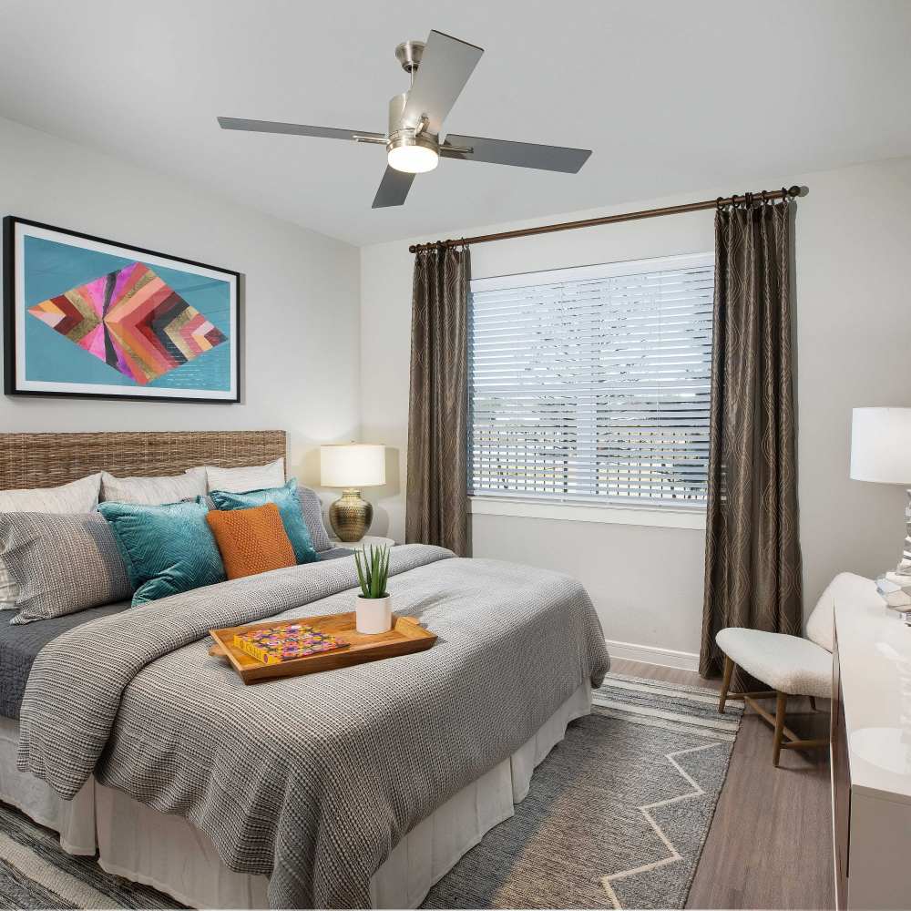 Cozy bedroom with ceiling fan and window at August Friendswood in Friendswood, Texas