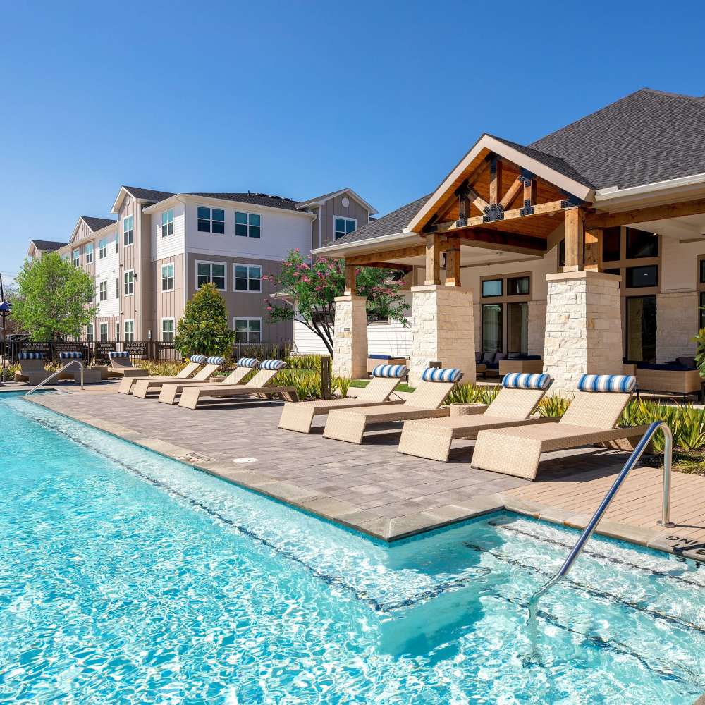 Resort-style pool with lounge chairs at August Friendswood in Friendswood, Texas