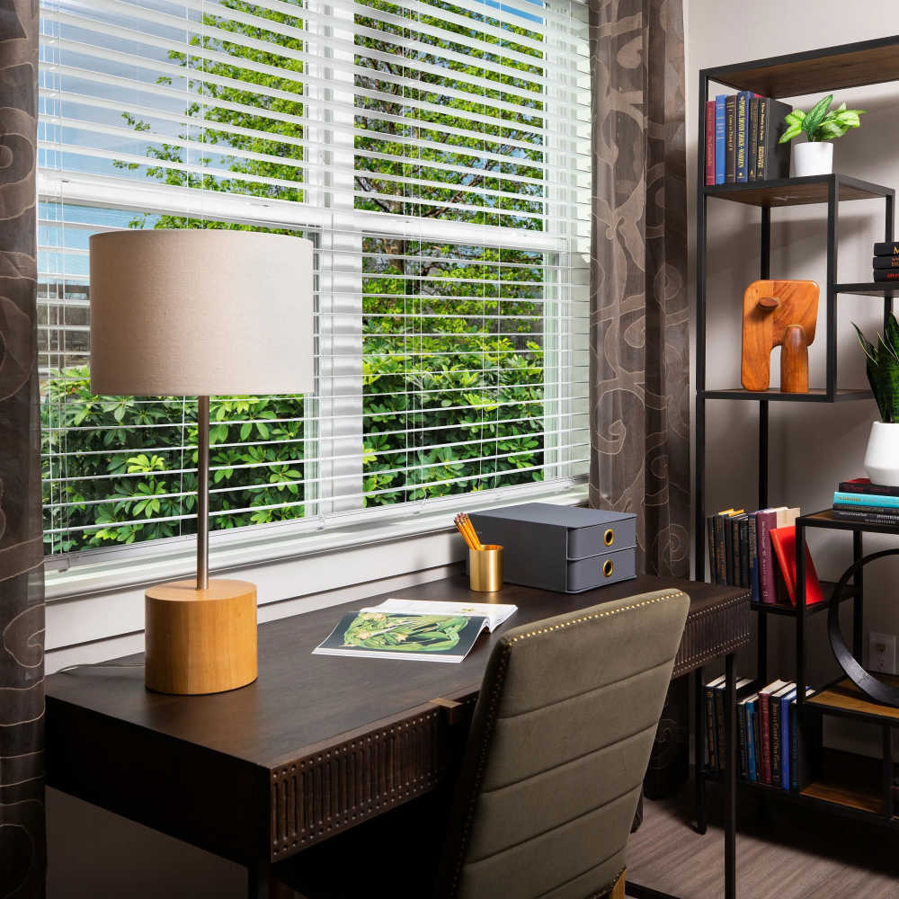 Desk with lamp and bookshelves at August Friendswood in Friendswood, Texas