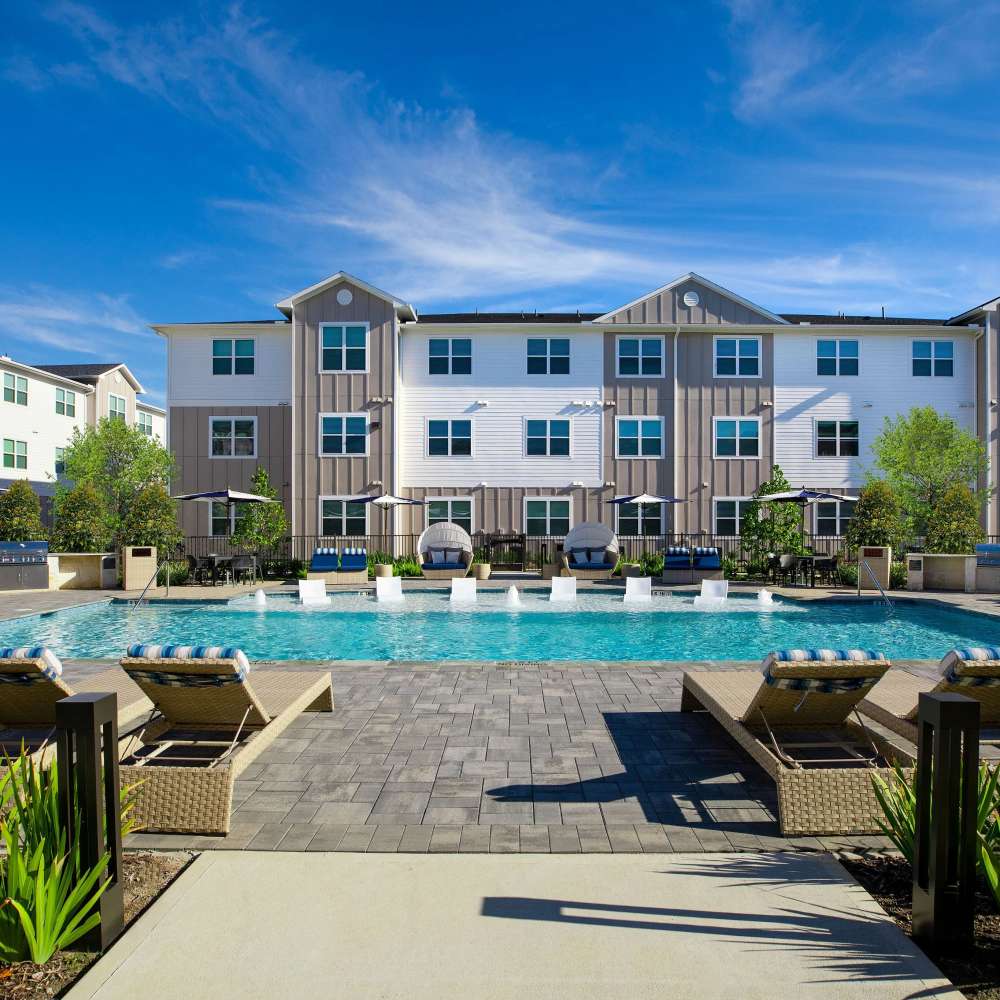Sparkling pool with lounge chairs at August Friendswood in Friendswood, Texas