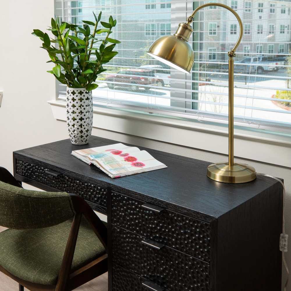 Stylish desk with lamp and plant at August Friendswood in Friendswood, Texas
