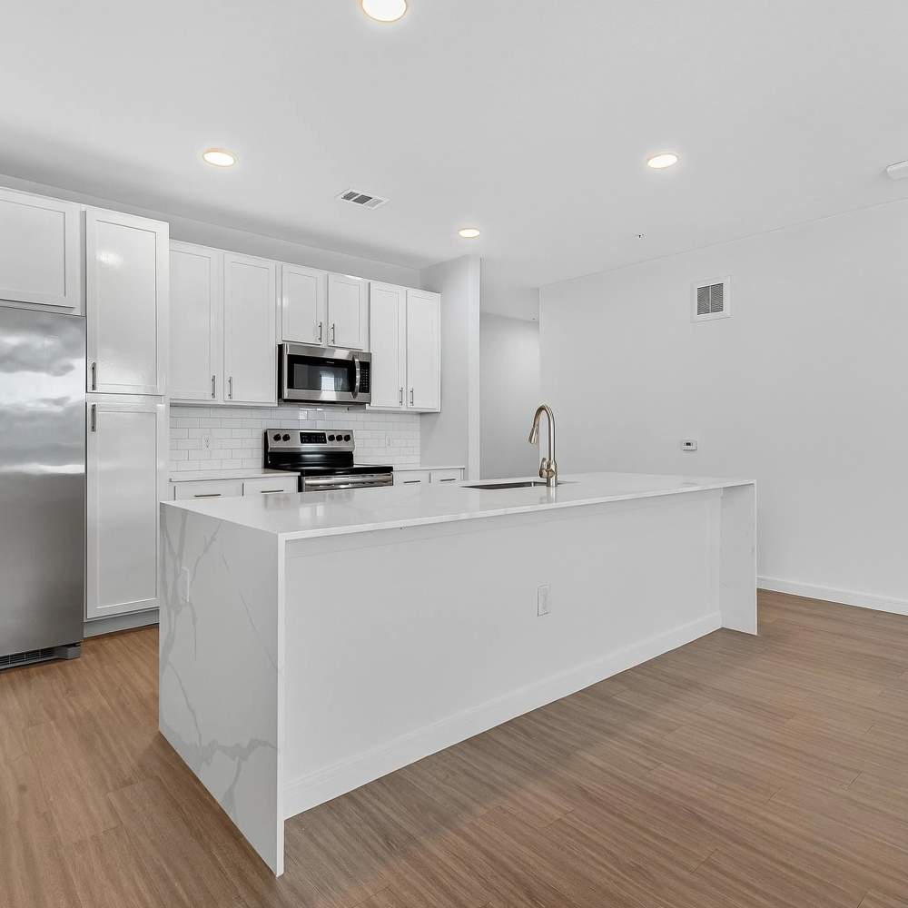 Open layout kitchen with granite island at August Friendswood in Friendswood, Texas