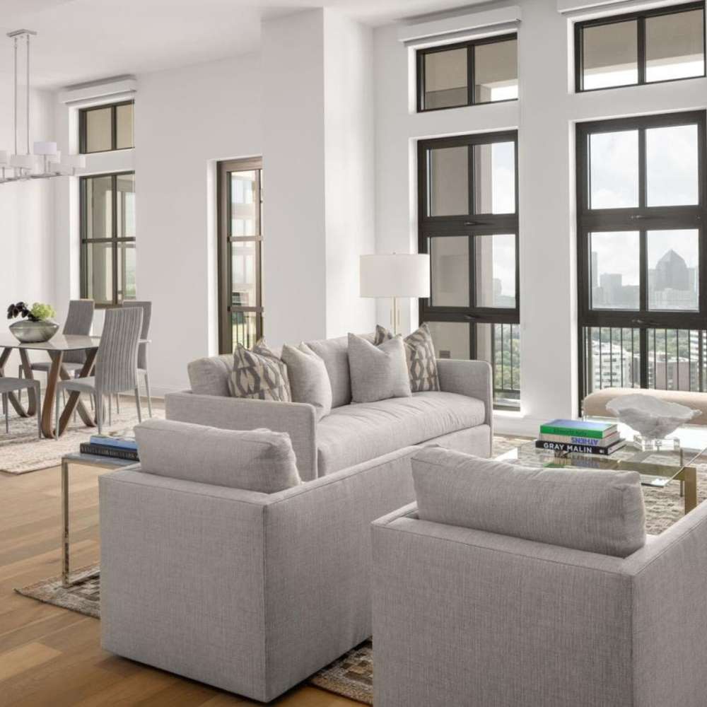 Modern living and dining area with floor-to-ceiling windows and city views at Novel Turtle Creek in Dallas, Texas