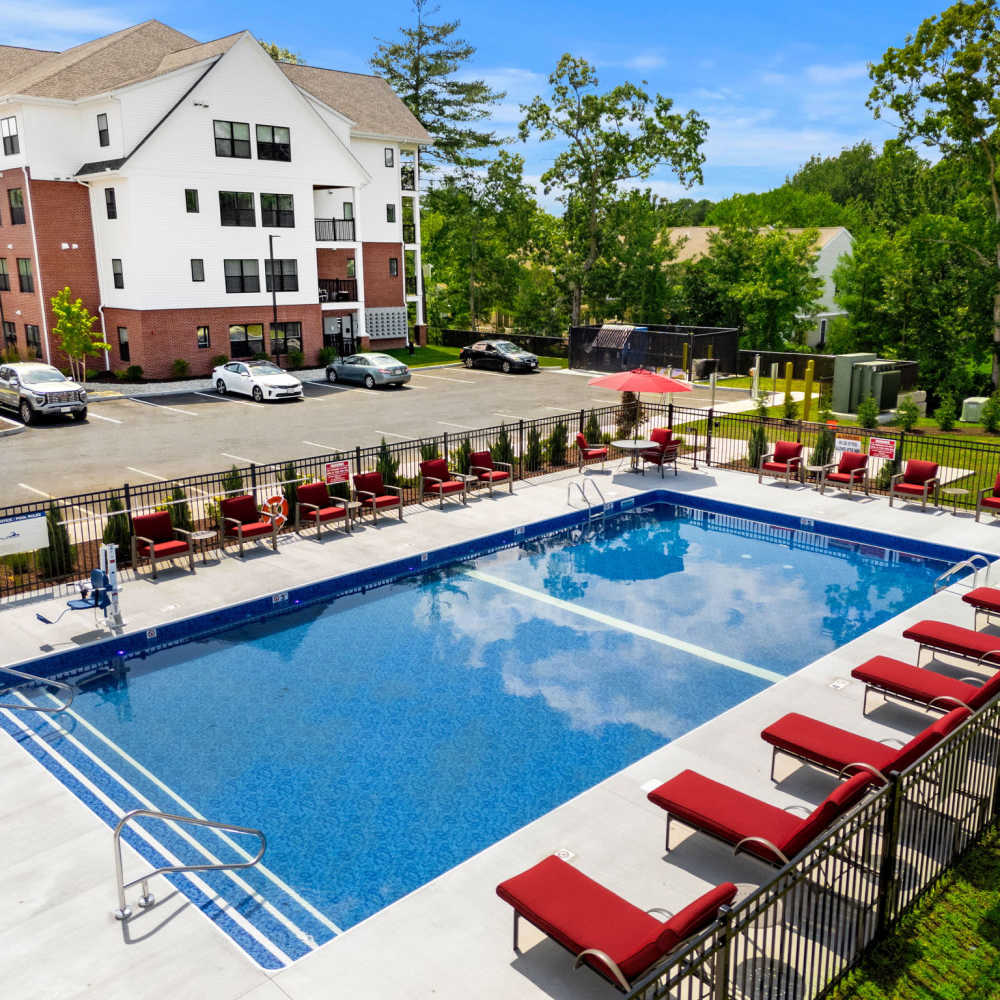 Outdoor resort-style swimming pool with lounge chairs and landscaped grounds at Middleborough Station in Middleborough, Massachusetts