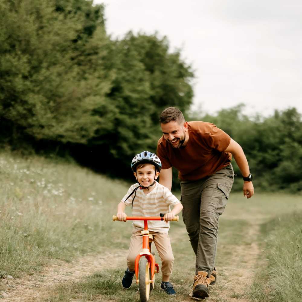 Man pushing a child on a bike at Emerald Properties in San Lorenzo, California