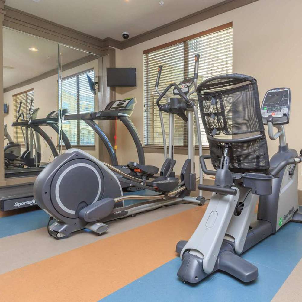 On-site fitness center with cardio equipment and mirrored workout area at Villages at Cypress in Houston, Texas