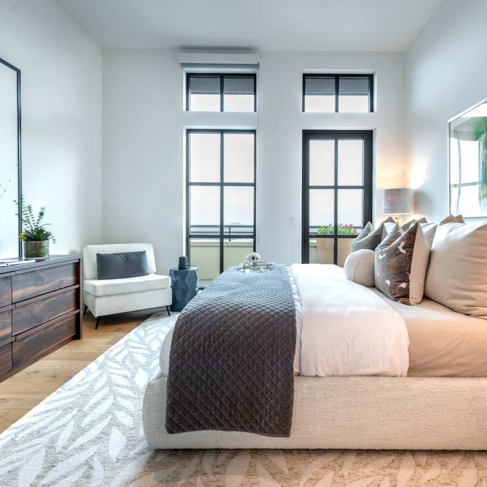Bright bedroom with plush bedding and hardwood flooring at Novel Turtle Creek in Dallas, Texas