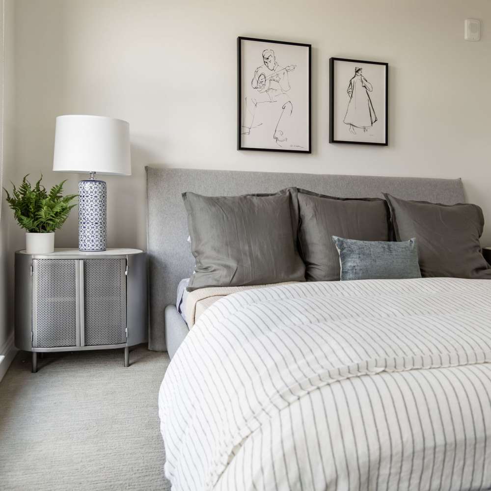 Cozy bedroom with gray bedding and decorative pillows at Novel Turtle Creek in Dallas, Texas
