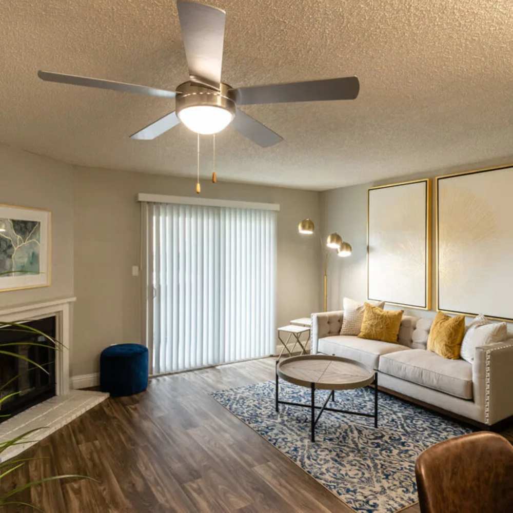 Two-Bedroom Apartments in Reno, Nevada - The Verge Apartments - Spacious Living Room with Fireplace, Sliding Glass Door, Ceiling Fan, Patterned Area Rug, And Neutral  Seating Verge in Reno, Nevada