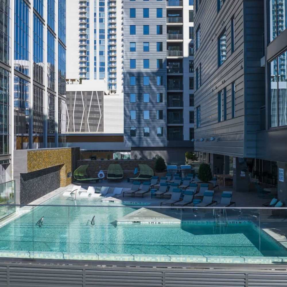 Glass pool surrounded by lounge chairs at Novel Midtown in Atlanta, Georgia