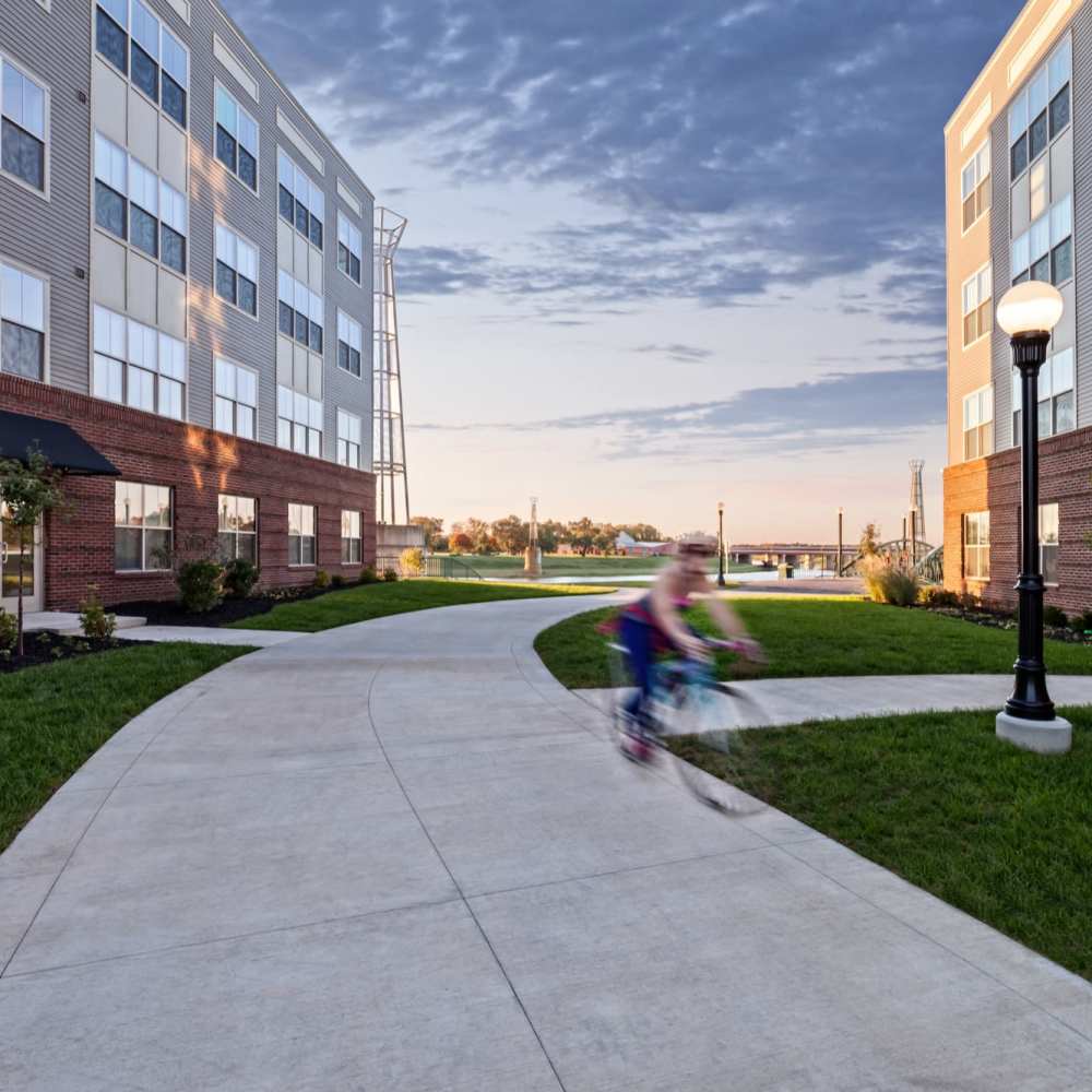 Resident biking on a path between buildings at Water Street Apartments in Dayton, Ohio
