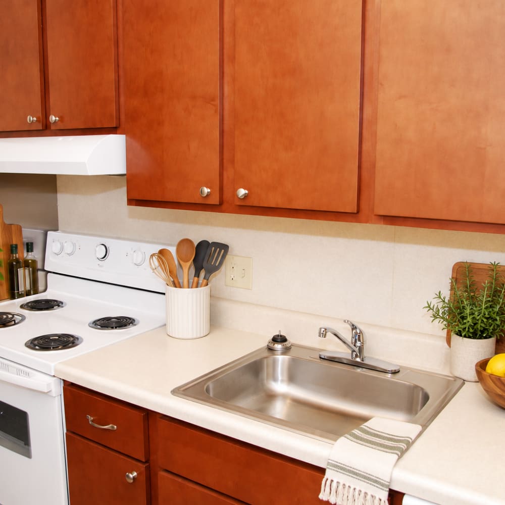 Apartment kitchen with wooden cabinetry and white appliances at Council Tower Apartments in Saint Louis,Missouri