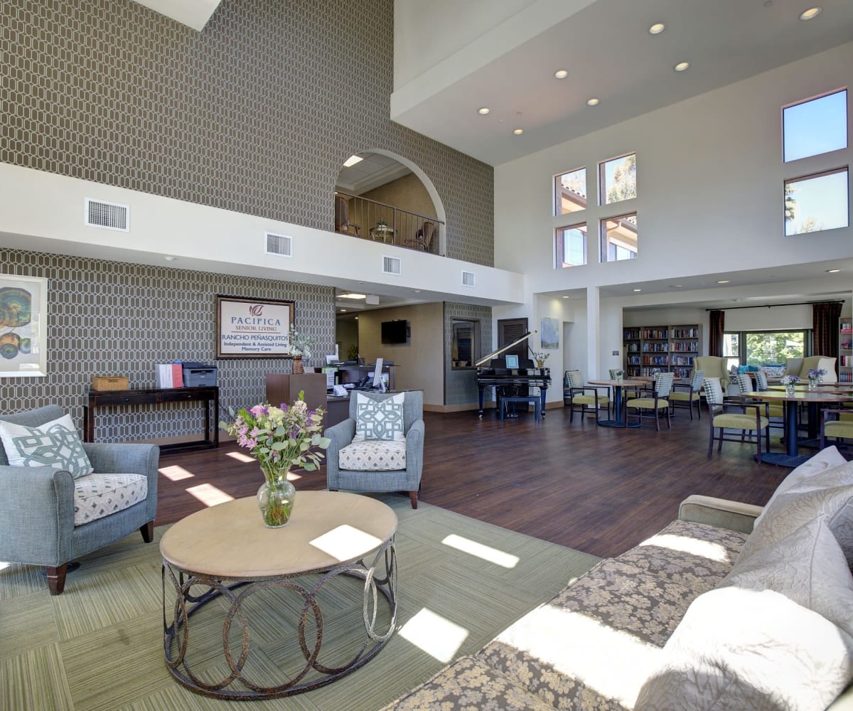 Lounge area with piano and multiple bookshelves at Pacifica Senior Living Rancho Peñasquitos in San Diego, California