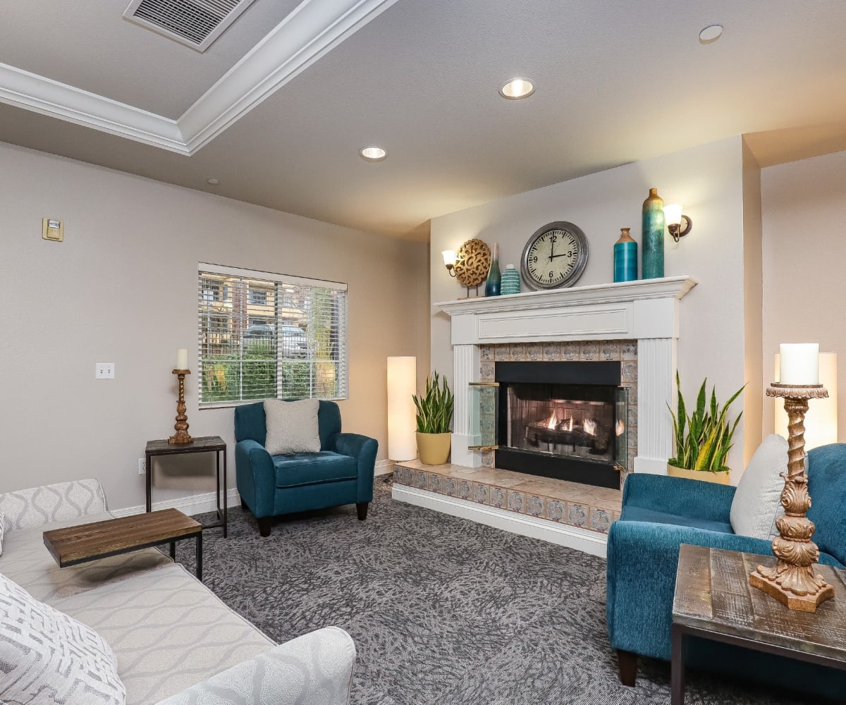 Resident lounge area with armchairs and cozy fireplace at Pacifica Senior Living Poway in Poway, California