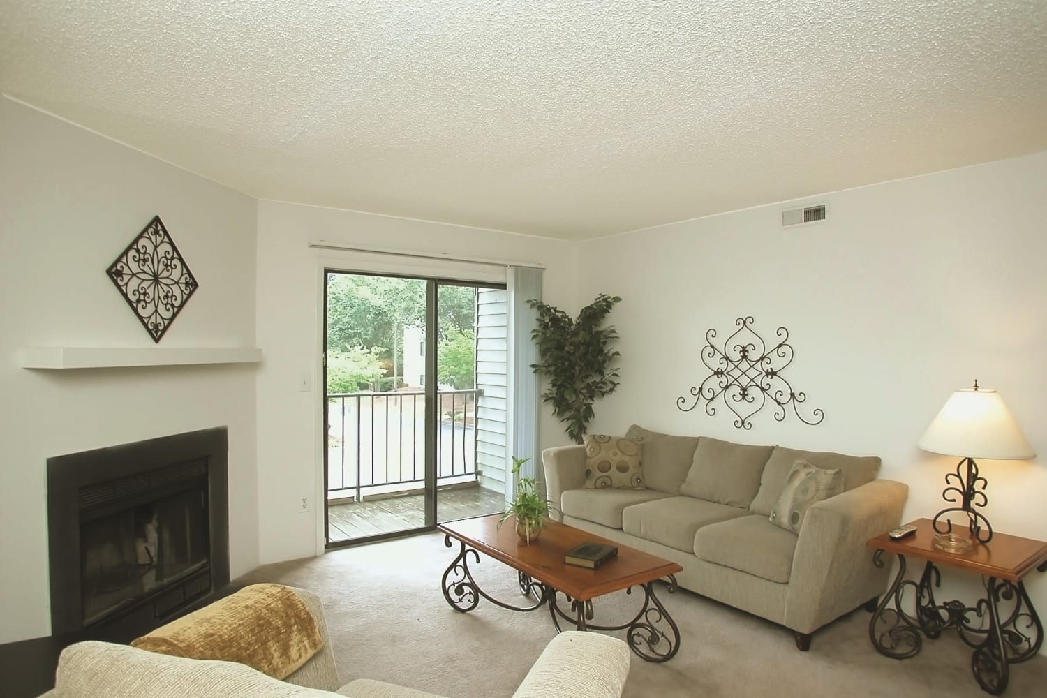 Living room with a fireplace and private patio access at Stonesthrow Apartment Homes in Greenville, South Carolina