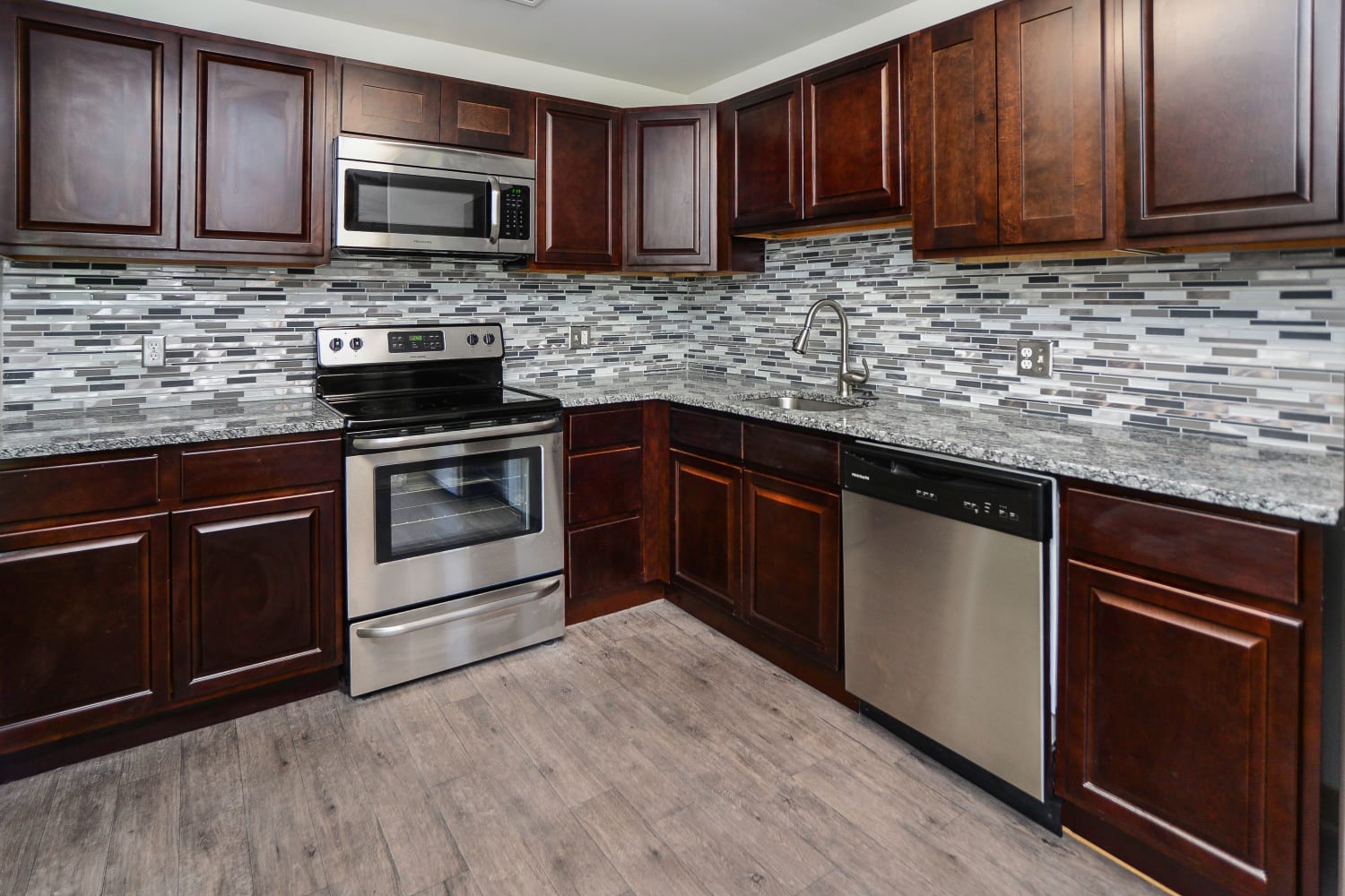 Contemporary kitchen with tile backsplash and stainless-steel appliances at Place One Apartment Homes in Plymouth Meeting, Pennsylvania