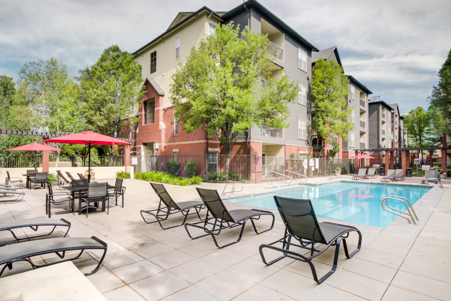 Apartment buildings in the background with lounge chairs and community pool in the foreground at Irving Schoolhouse Apartments in Salt Lake City, Utah