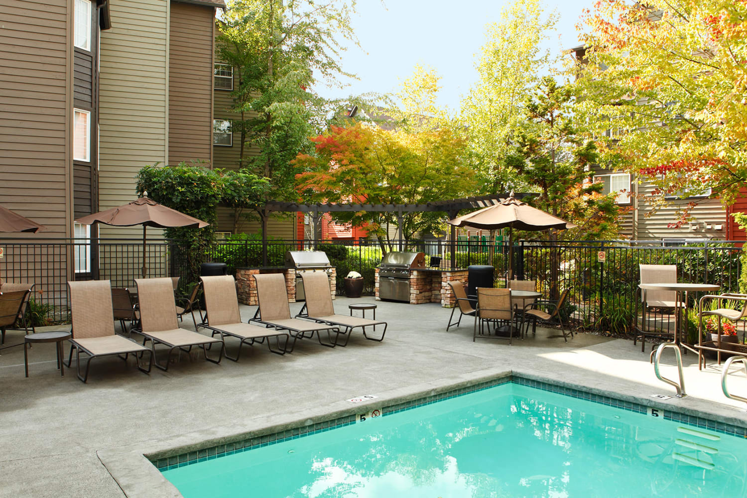 Dazzling blue pool with nearby seating at Redmond Place Apartments in Redmond, Washington