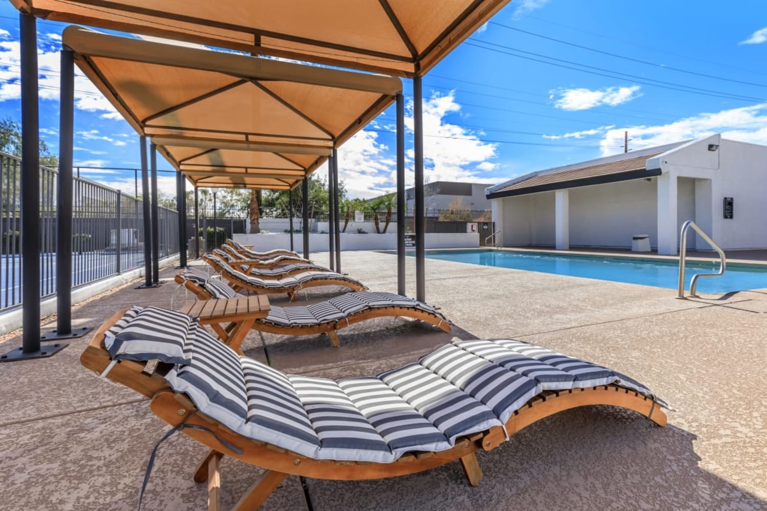 Covered lounge chairs by the pool at Station 21 Apartments in Mesa, Arizona