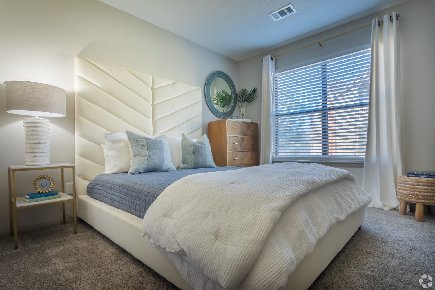 Cozy layouts and draped windows in a model home's bedroom at The Cooper in Mount Pleasant, South Carolina