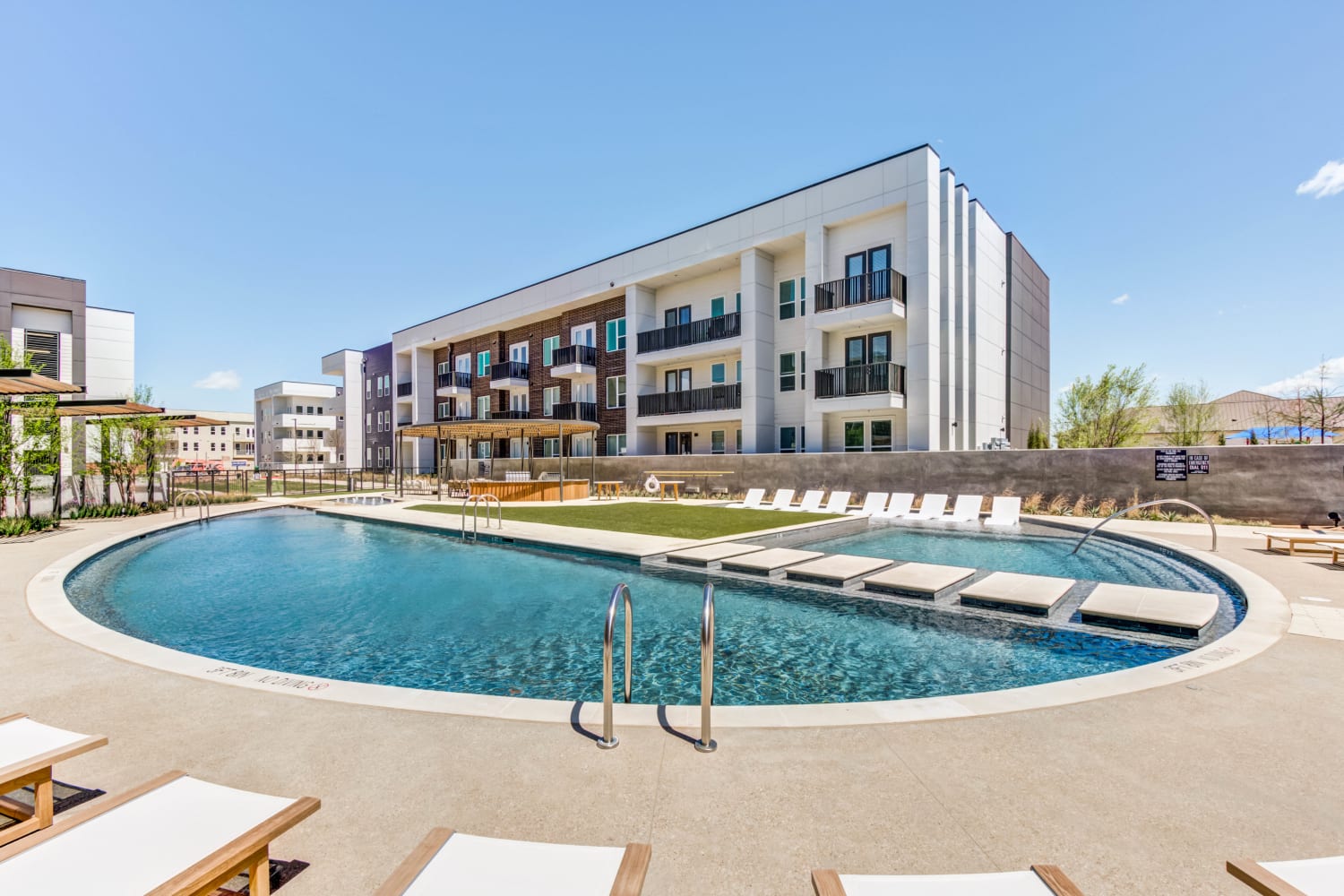 Resort-style pool with poolside seating at Mezzo Apartments in Aubrey, Texas