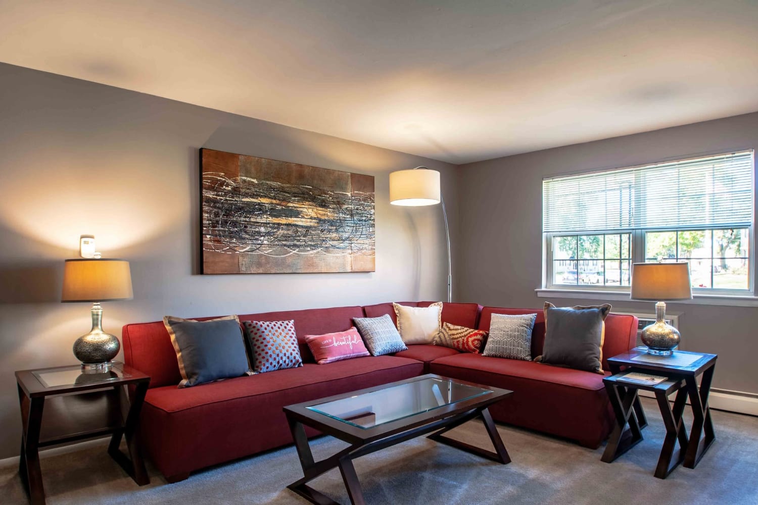 Living room with wrap around couch and large window at Camp Hill Plaza Apartment Homes 