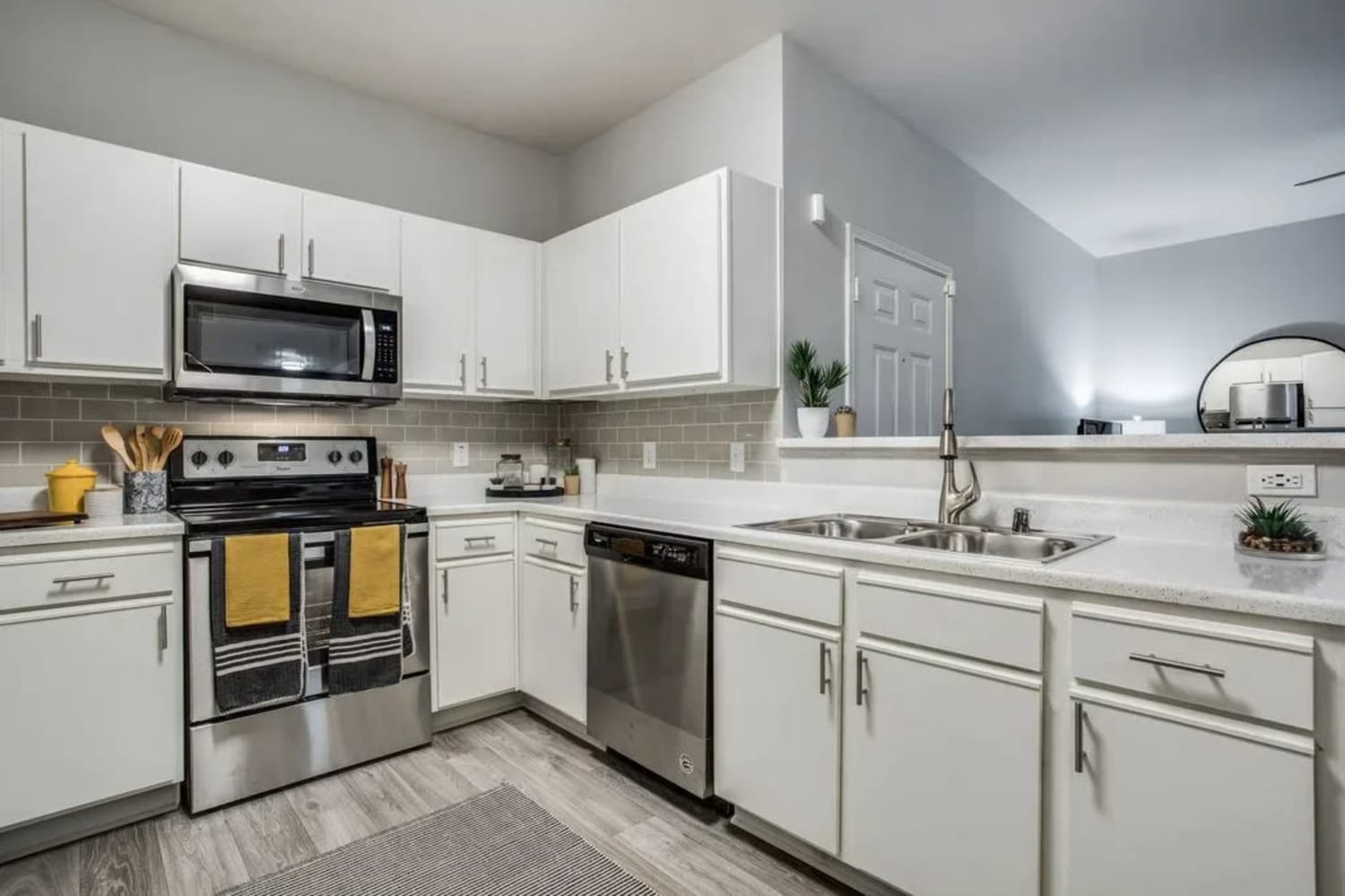 White cupboards and stainless-steel appliances in an apartment kitchen at Oak Grove Apartments in Houston, Texas
