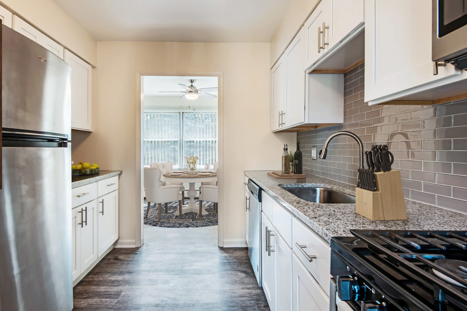 Bright, modern kitchen with granite countertops and a glass tile backsplash at Emerald Springs Apartments in Painted Post, New York