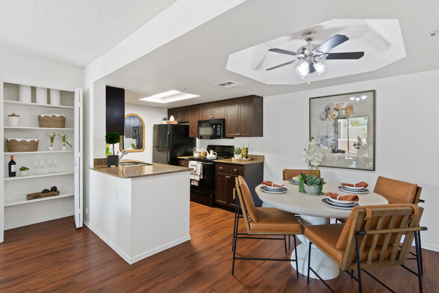 Fully-equipped kitchen with white cabinetry and wood-style floors at Casa Santa Fe Apartments in Scottsdale, Arizona