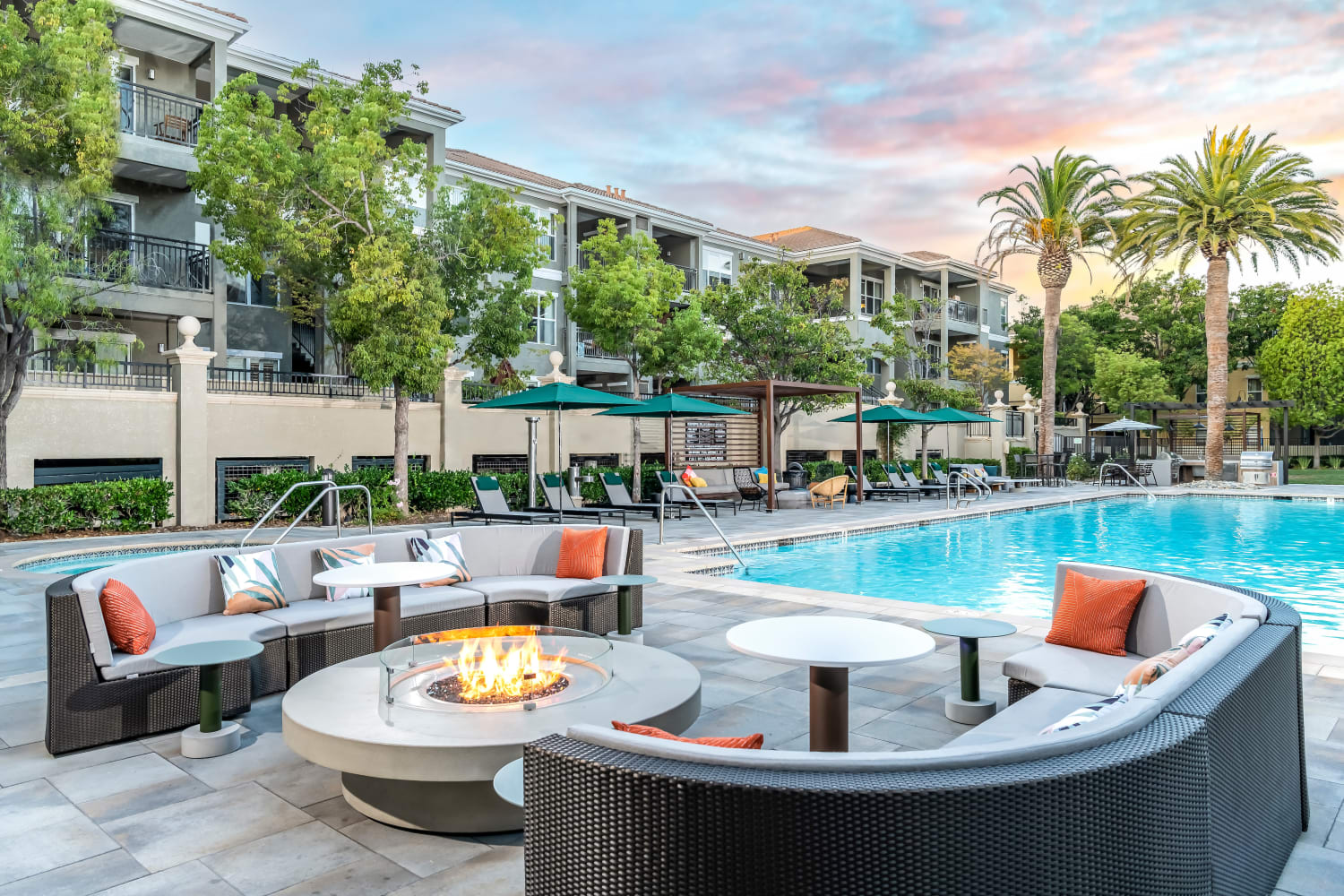 Community sitting area with comfortable couches beside pool at The Carlyle in Santa Clara, California