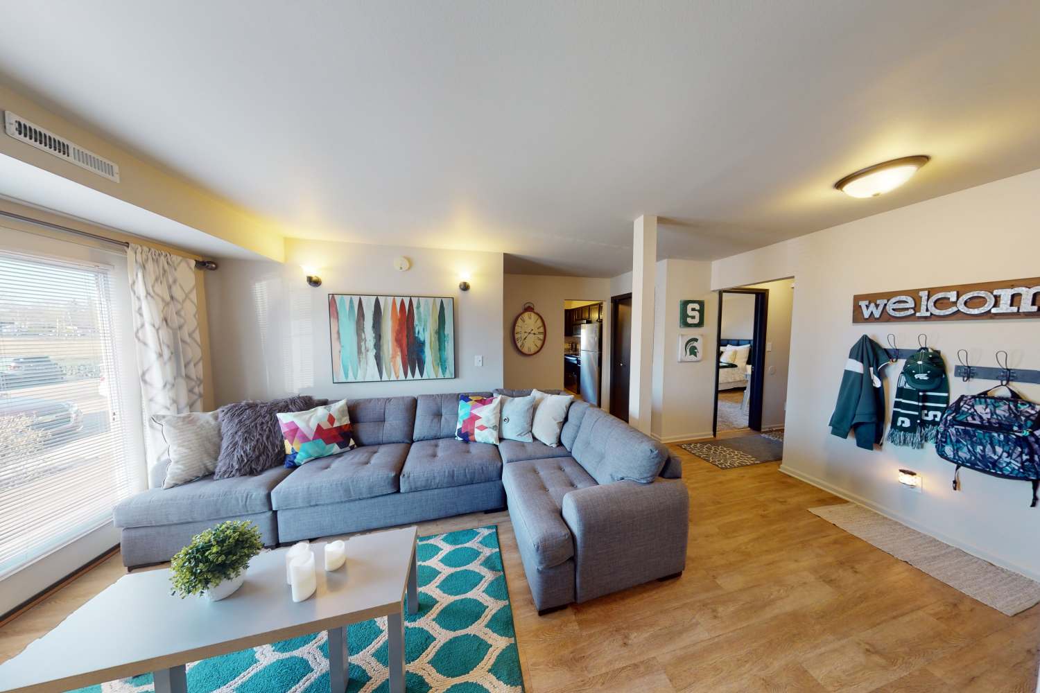 Spacious living room with hardwood floors and gray sectional at The Quarters at East Lansing in East Lansing, Michigan