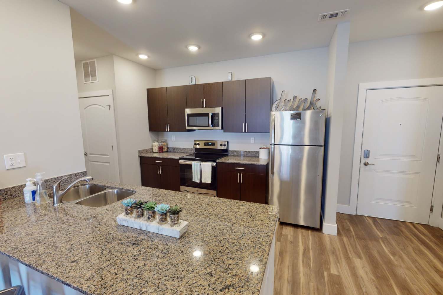 Apartment kitchen with hardwood floors and stainless-steel appliances at The Quarters at Bloomington in Bloomington, Indiana