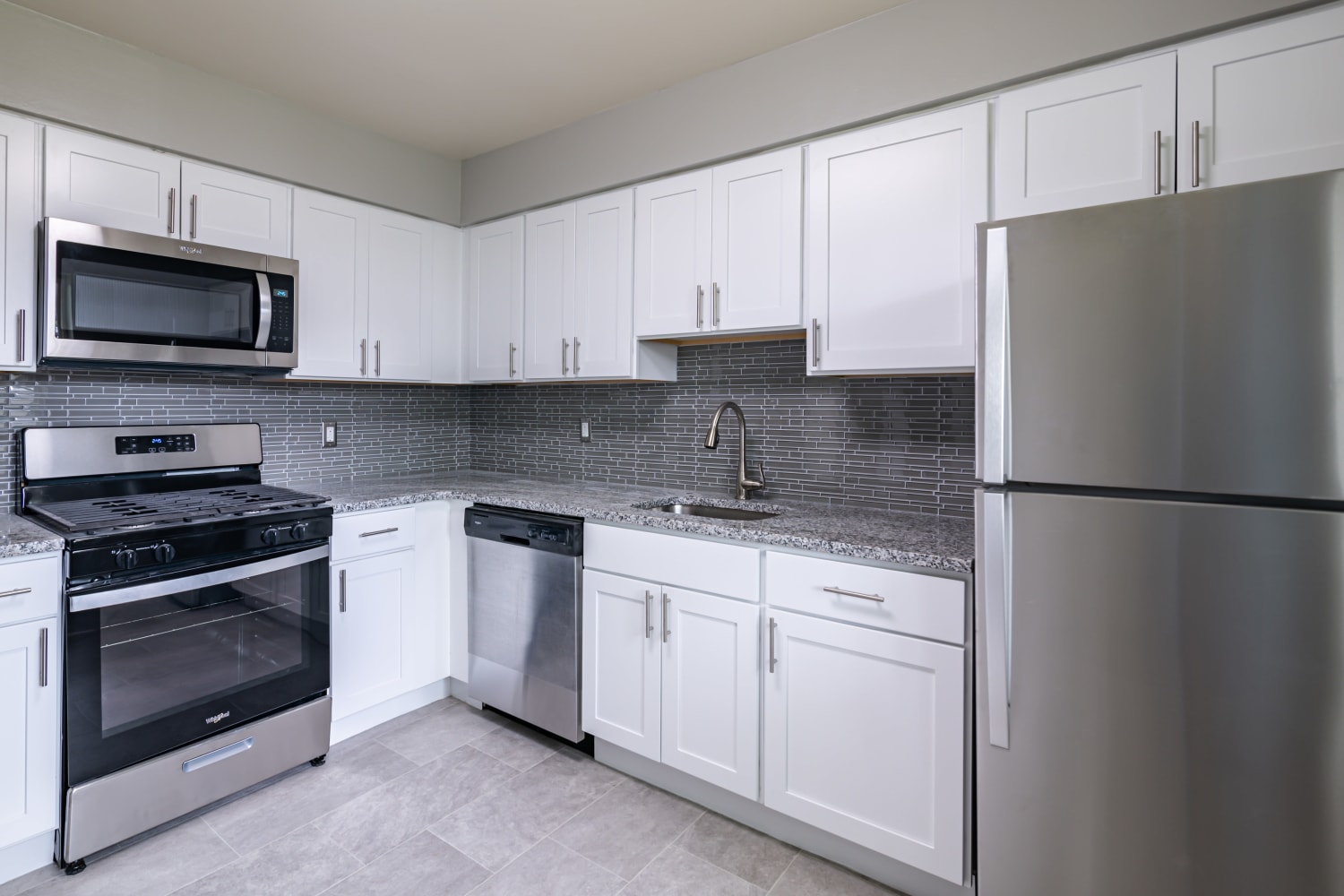 Upgraded kitchen with white cabinets, stainless appliances, and granite countertops