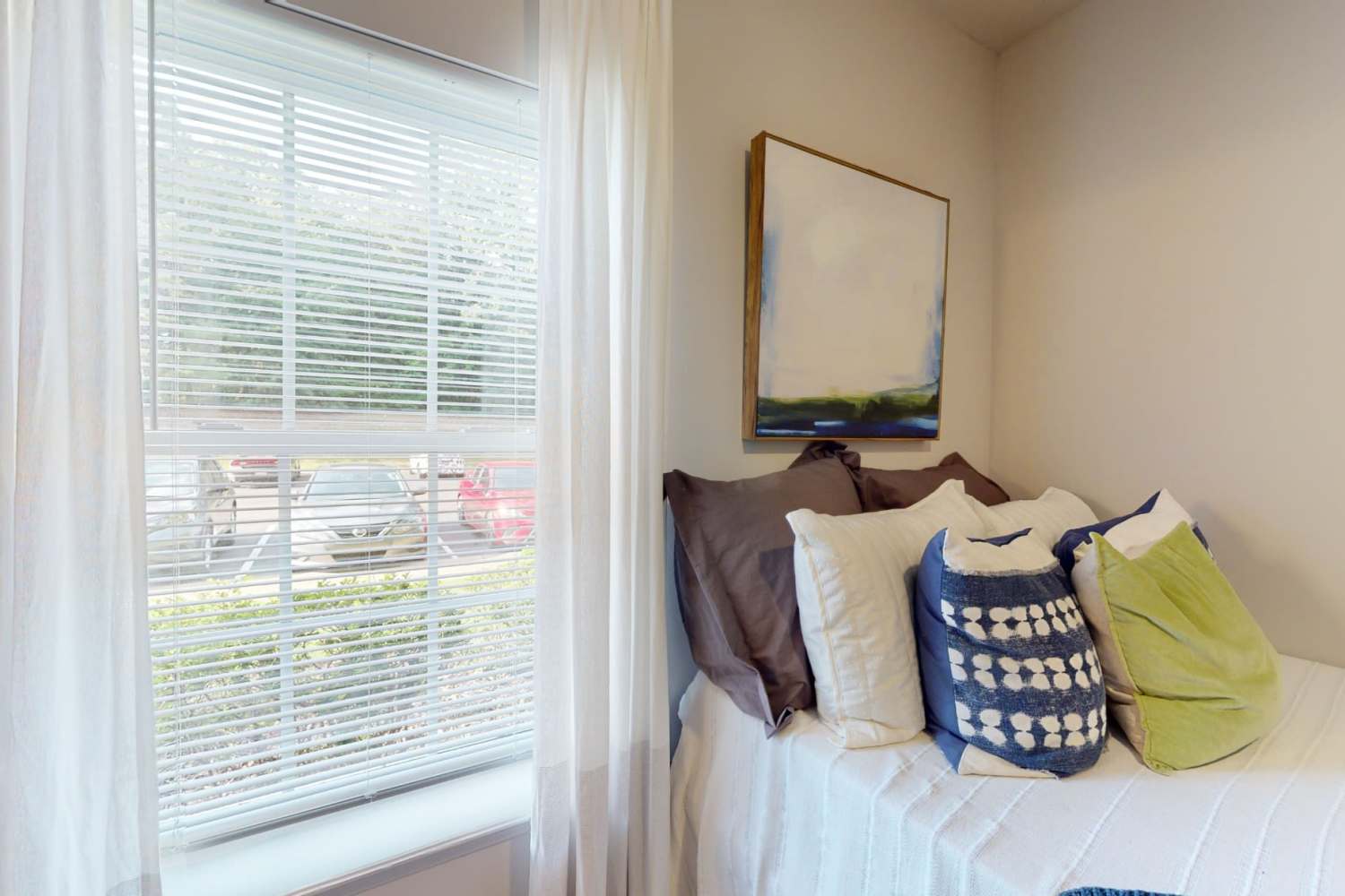 Bed with multiple throw pillows next to the window at The Quarters at Oxford in Oxford, Mississippi