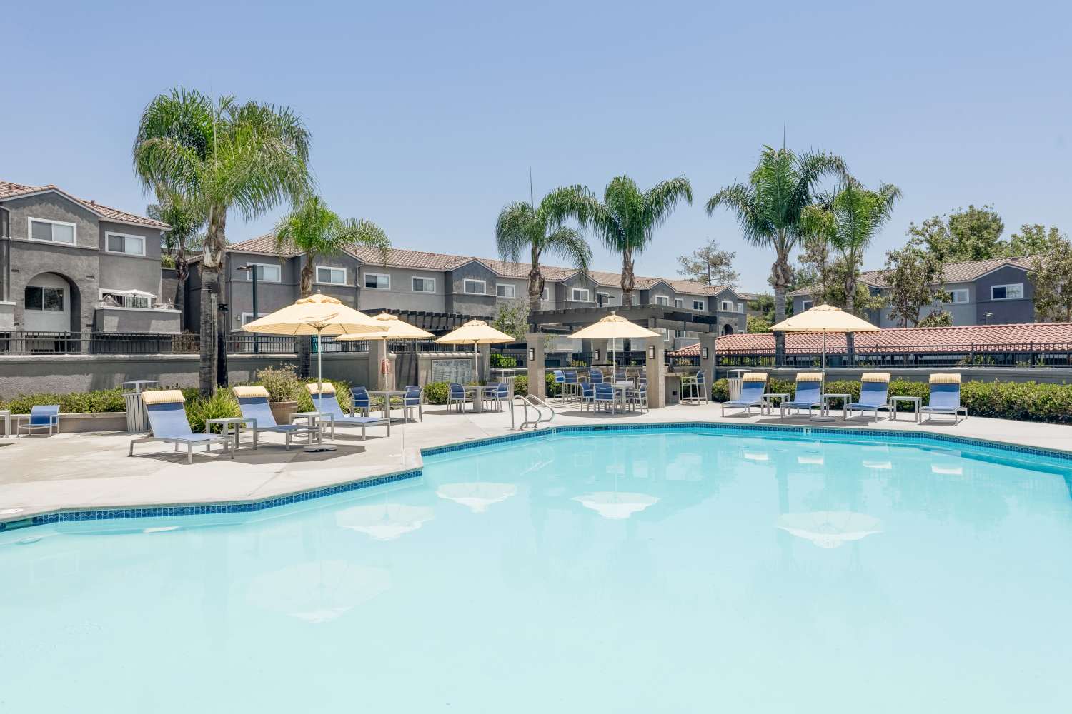 Swimming pool with sun loungers and shade at Madrid Apartments in Mission Viejo, California