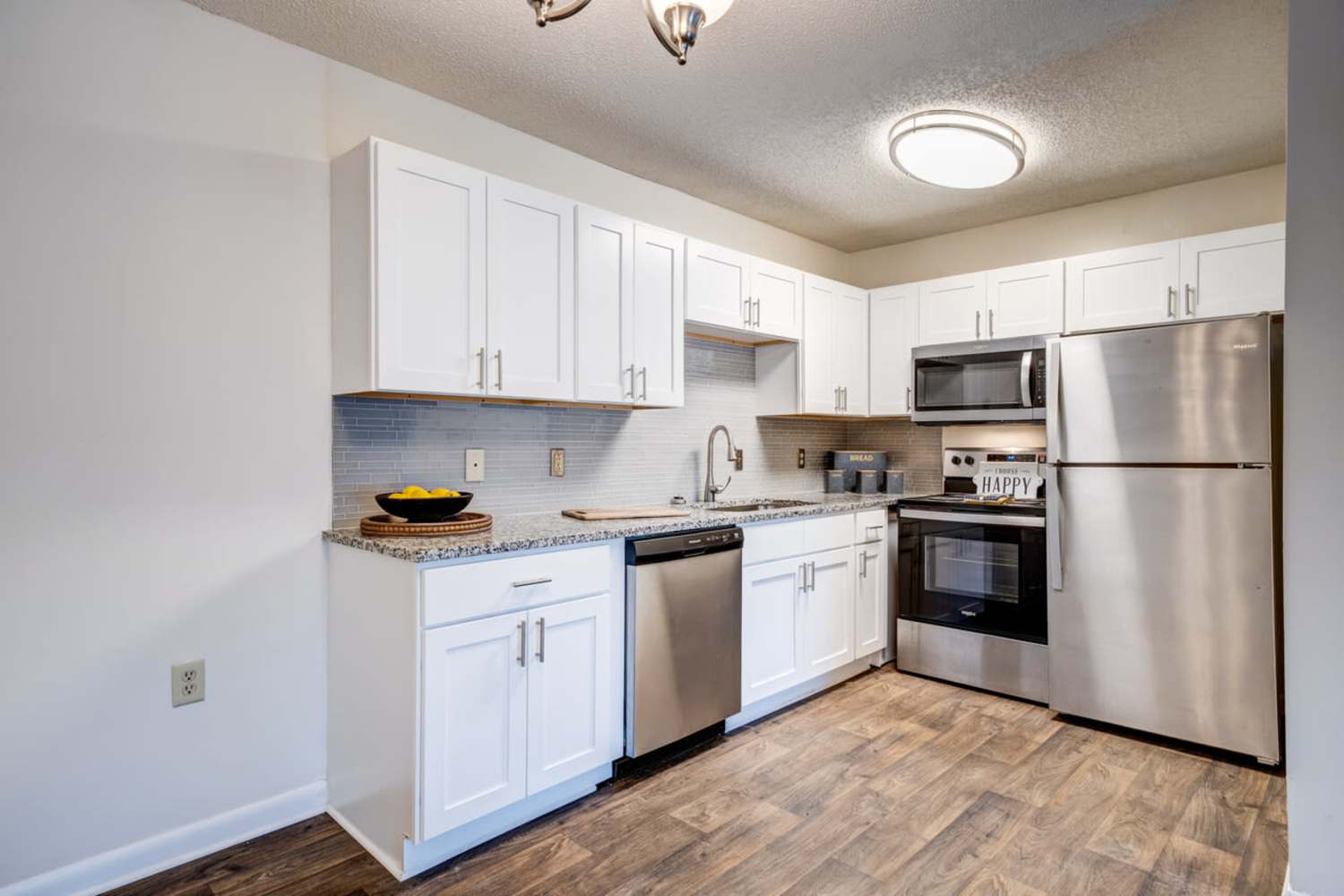 Cozy kitchen with red granite countertop, shiny cabinetry, refrigerator and a dishwasher at Ridgeview Apartment Homes in Reading, Pennsylvania