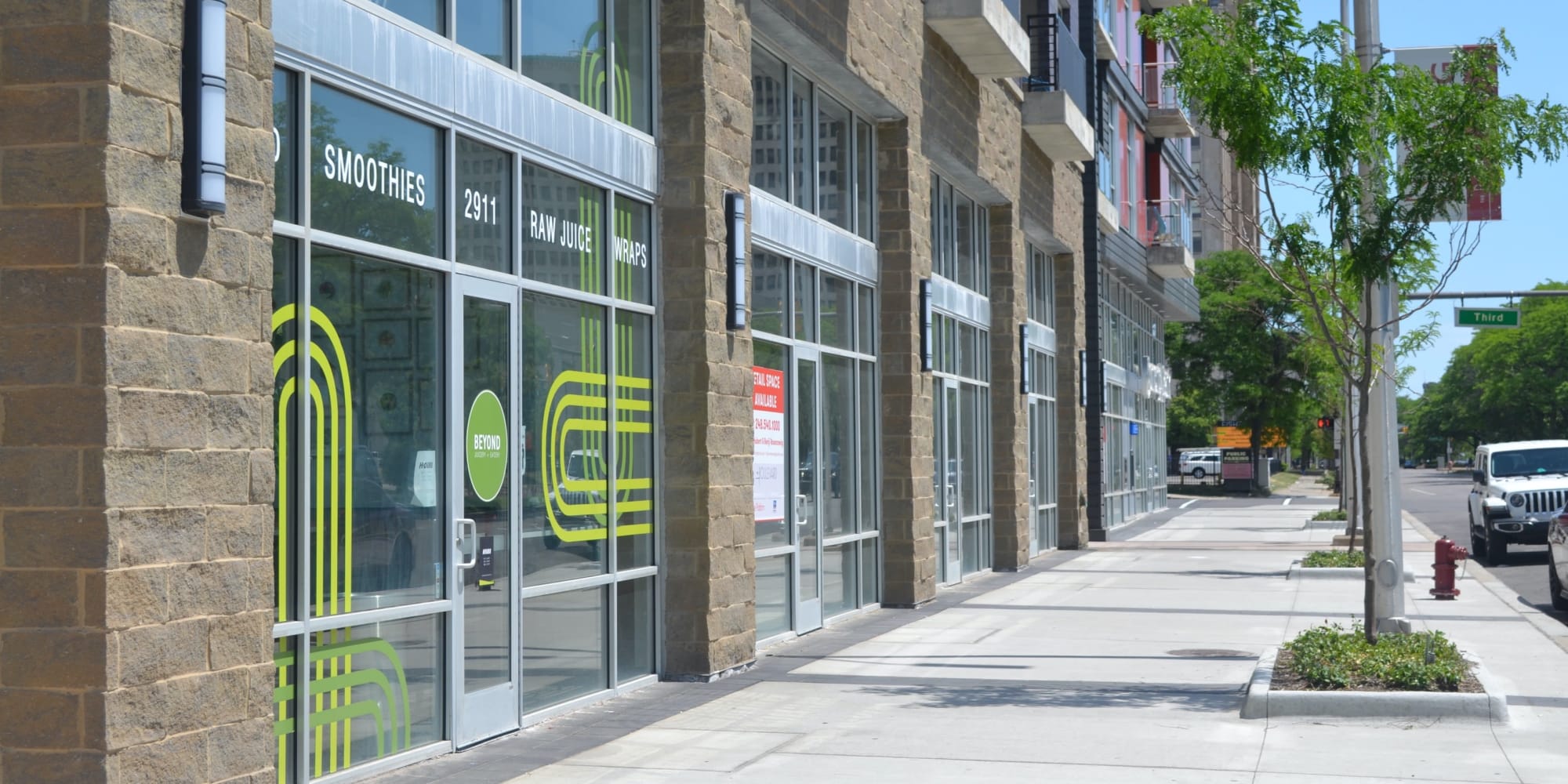 Sidewalk in front of retail spaces with glass storefronts at The Boulevard in Detroit, Michigan