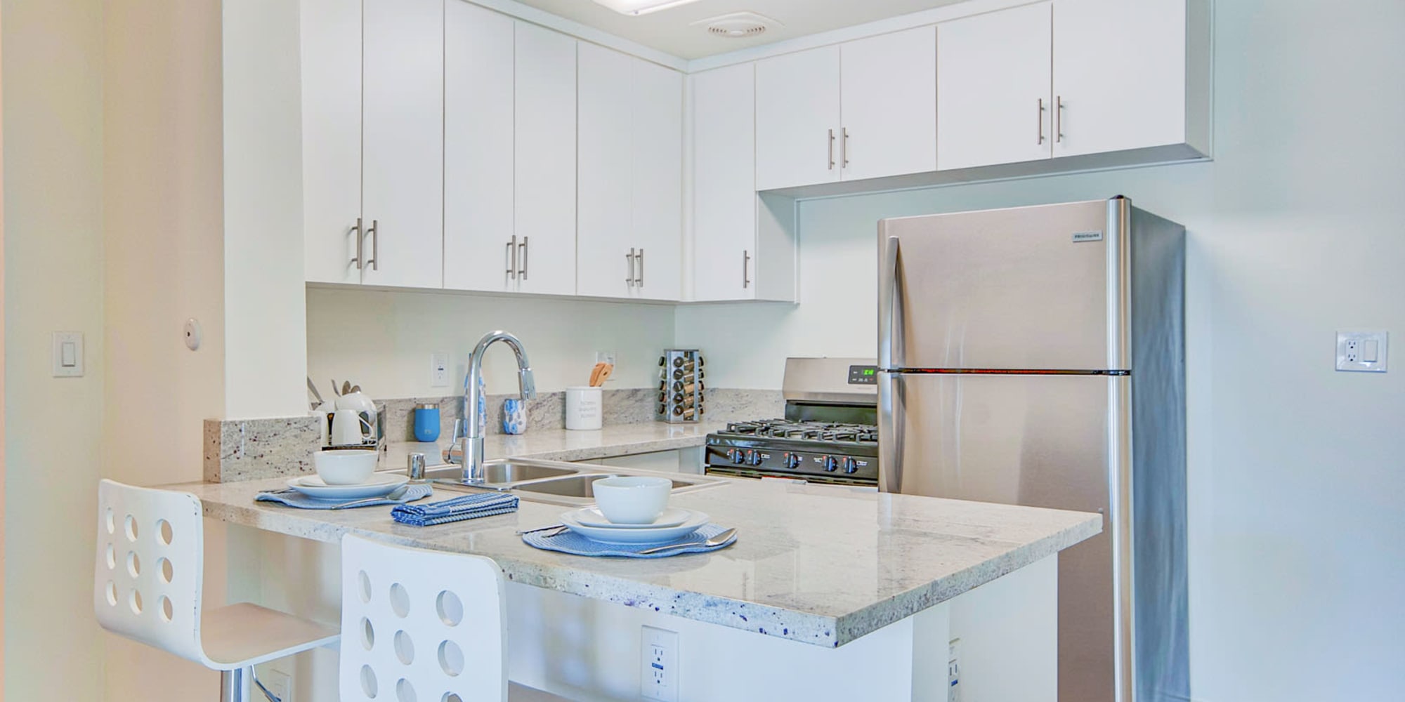Model apartment's kitchen with stainless-steel appliances and a breakfast bar at Villa Vicente in Los Angeles, California
