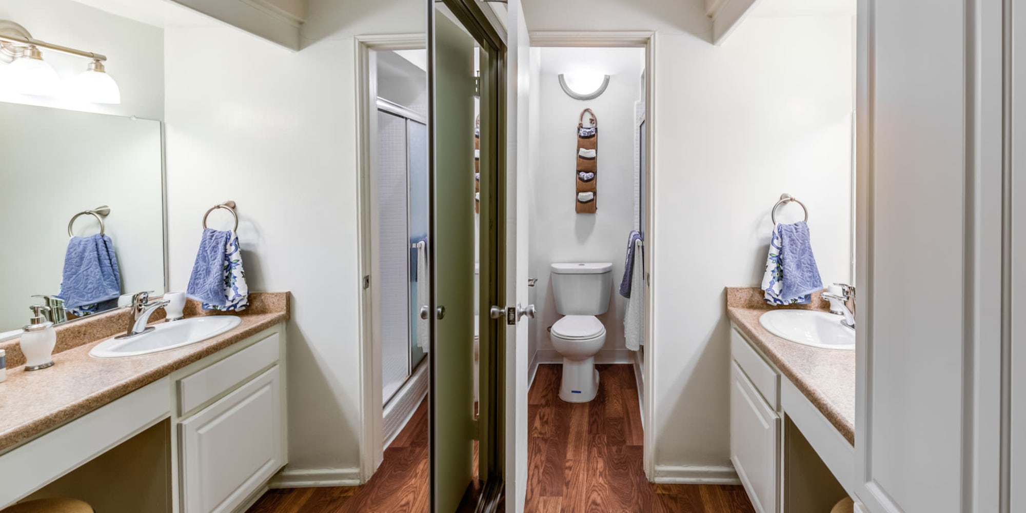 Mirrored closet doors and a large vanity mirror in the primary bathroom of a model apartment at Villa Vicente in Los Angeles, California