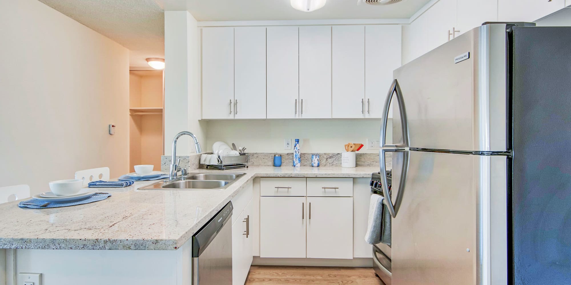 Bright white cabinetry and granite countertops in a model home's kitchen at Villa Vicente in Los Angeles, California