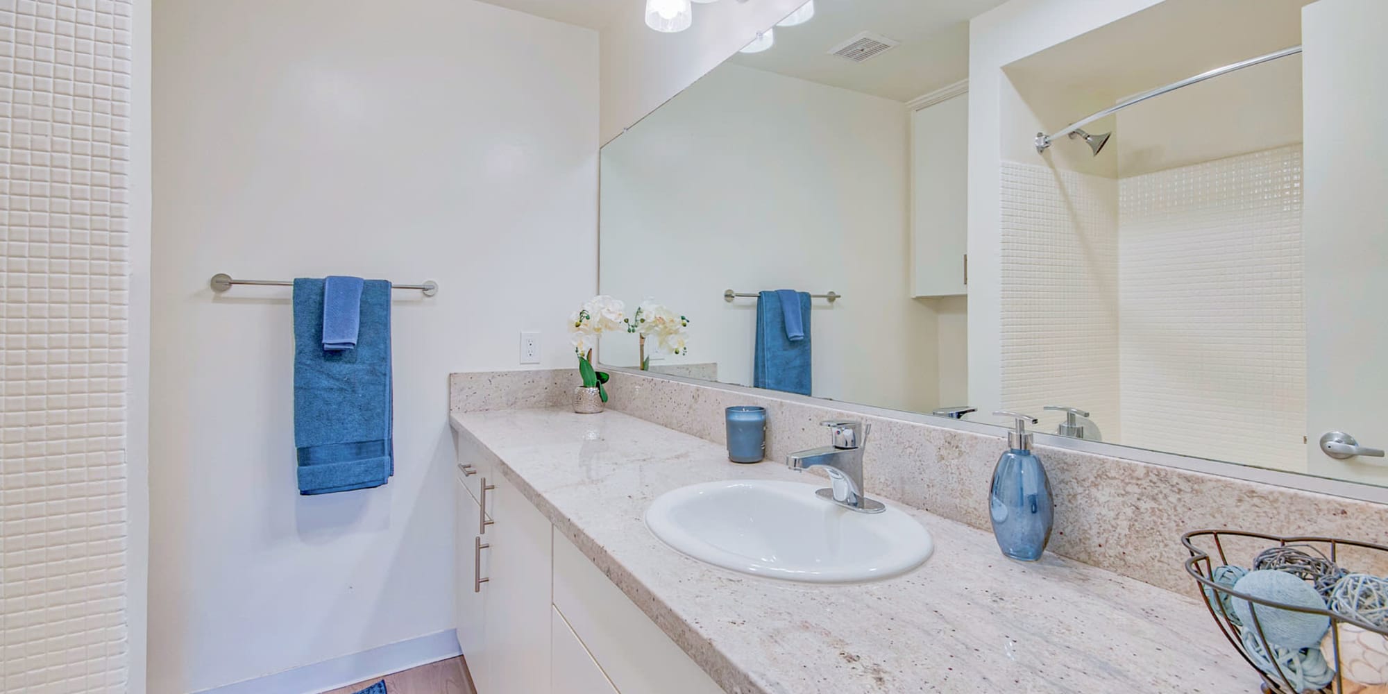 Expansive granite countertop and a custom tiled shower in a model home's bathroom at Villa Vicente in Los Angeles, California