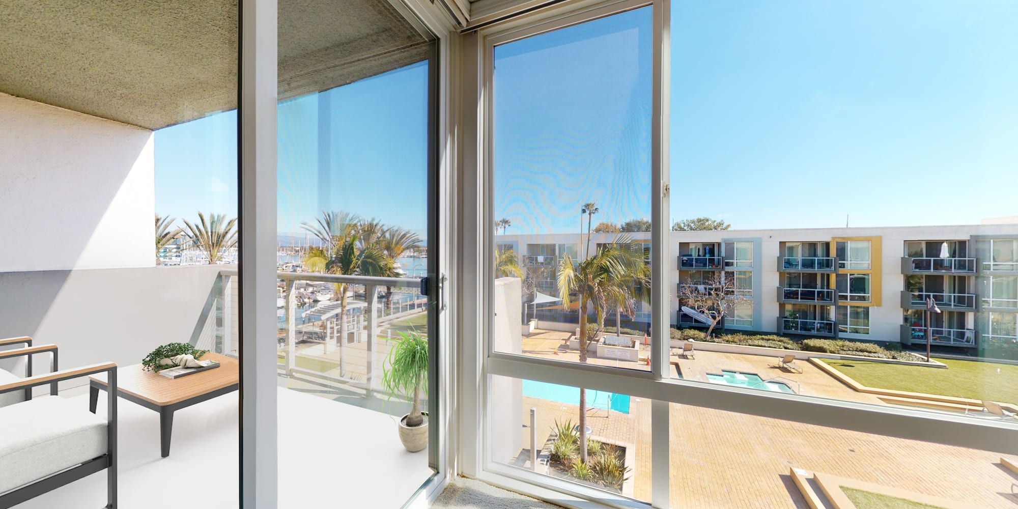 Living room with floor-to-ceiling windows and balcony with views of the marina at Waters Edge at Marina Harbor in Marina del Rey, California