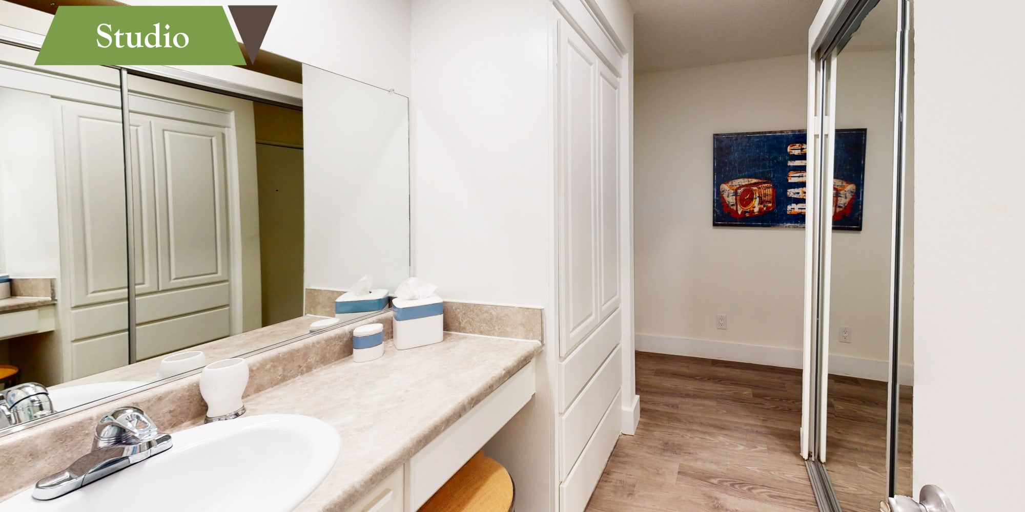 Mirrored closet doors and a large vanity mirror in the primary bathroom of a model apartment at Villa Vicente in Los Angeles, California