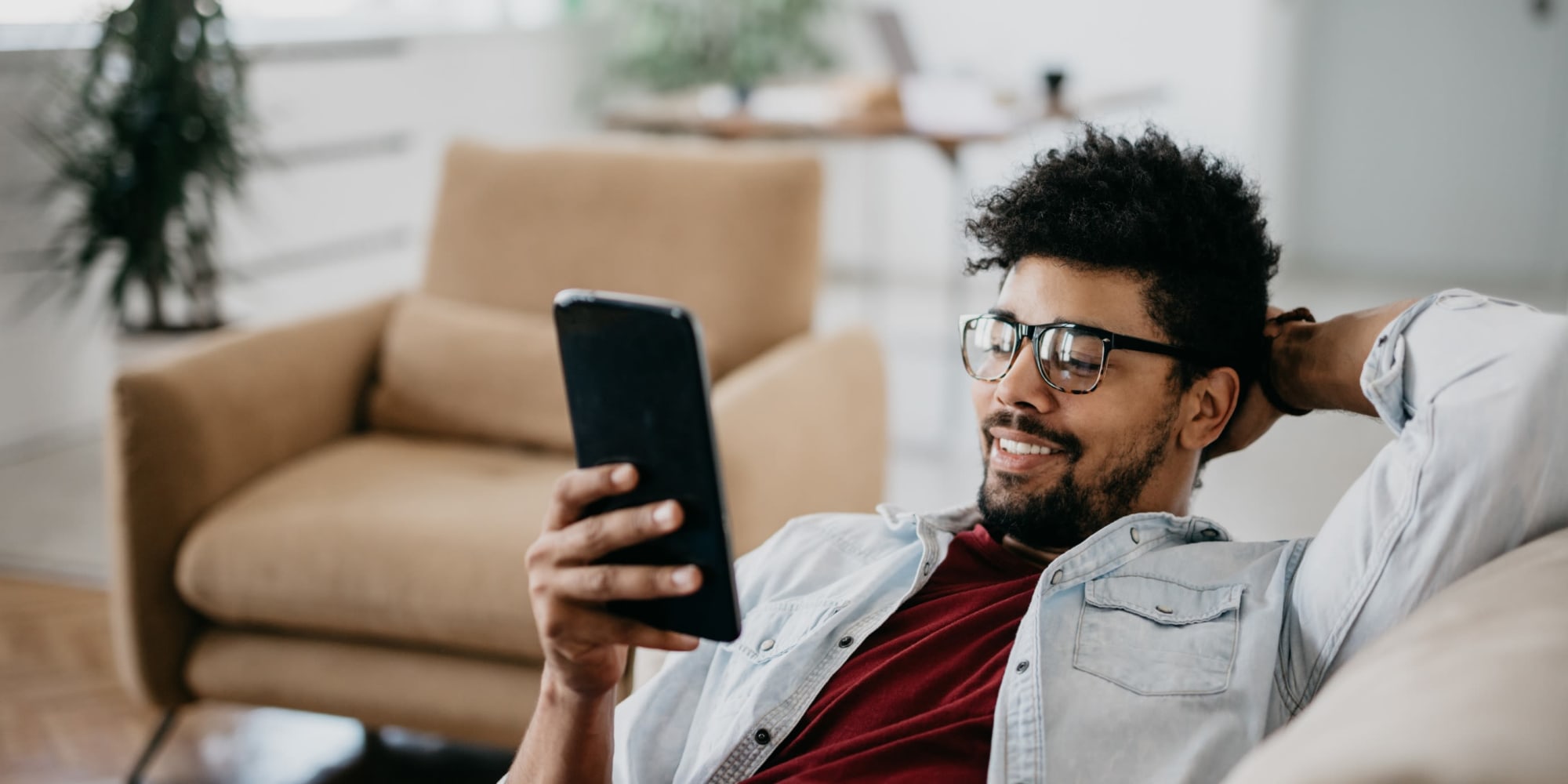 Man Reclining on a Couch and Looking at his Phone | 1221 Vallejo Apartments in Novato, California
