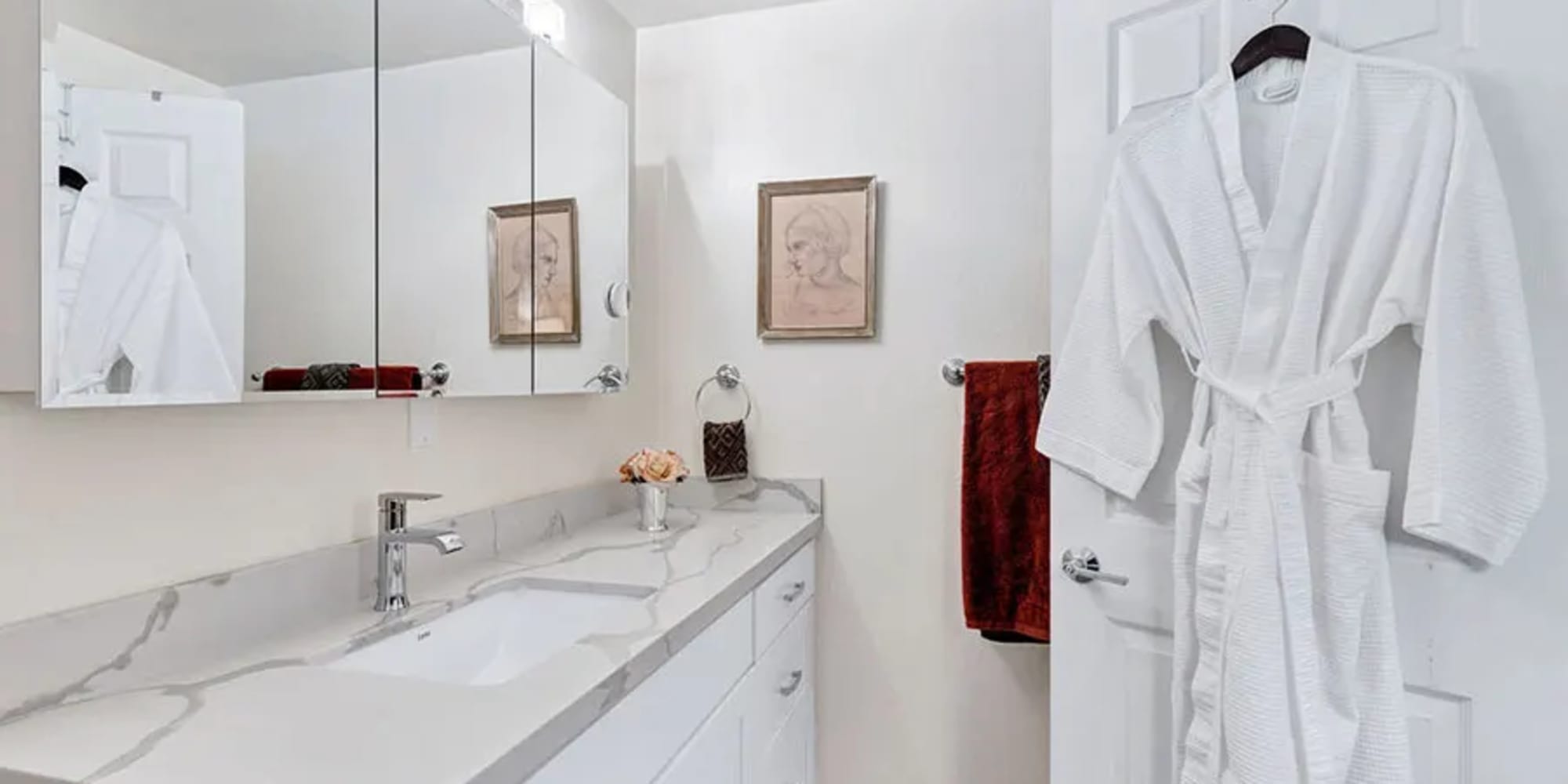 An apartment bathroom with a large counter and white cabinets at Silverado Gardens in Napa, California